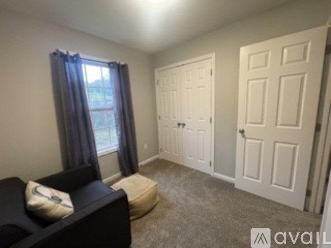A living room with a black couch and a window with curtains.