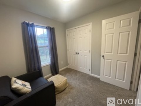 A living room with a black couch and a window with curtains.