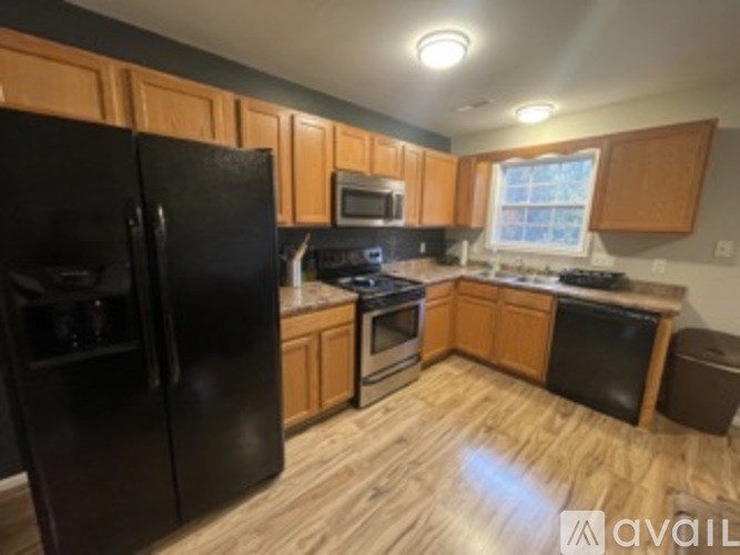 A kitchen with black appliances and wooden cabinets.