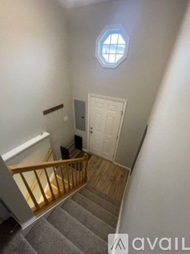 A staircase with a wooden handrail and a white door at the top.