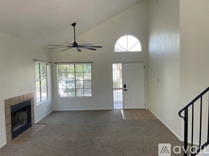 A living room with a fireplace and a ceiling fan.