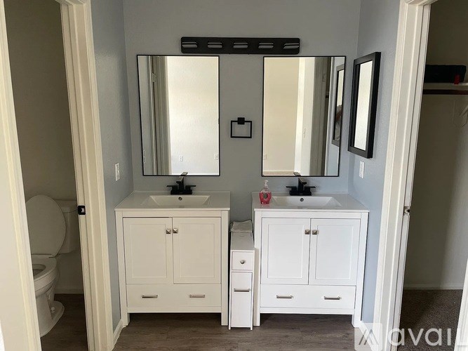 A bathroom with a white vanity and a large mirror.