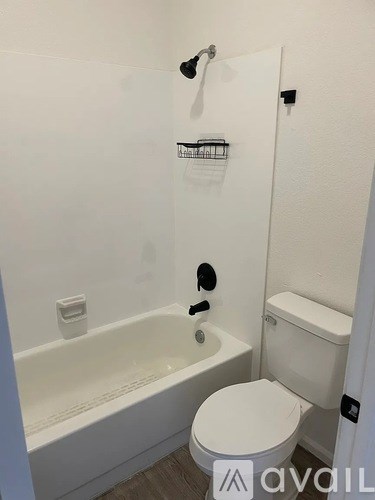 A white toilet sits next to a white bathtub in a small bathroom.