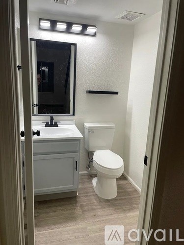 A bathroom with a toilet, sink, and mirror.