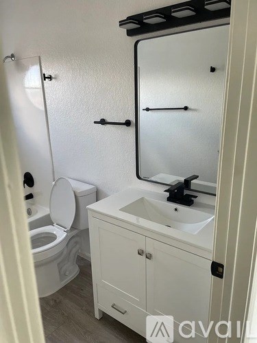 A white bathroom with a toilet, sink, and mirror.
