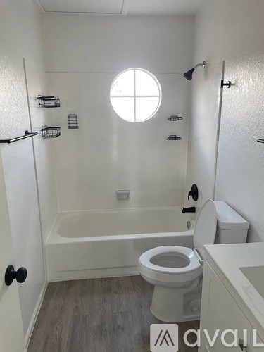 A bathroom with a toilet, tub, and a window.