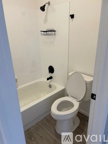 A white toilet in a bathroom with a white tub and a white shower curtain.