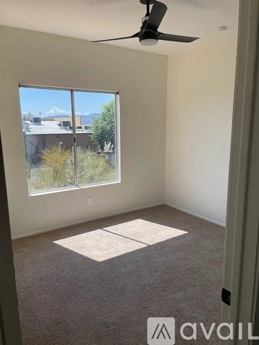 A room with a fan and a window overlooking a cityscape.