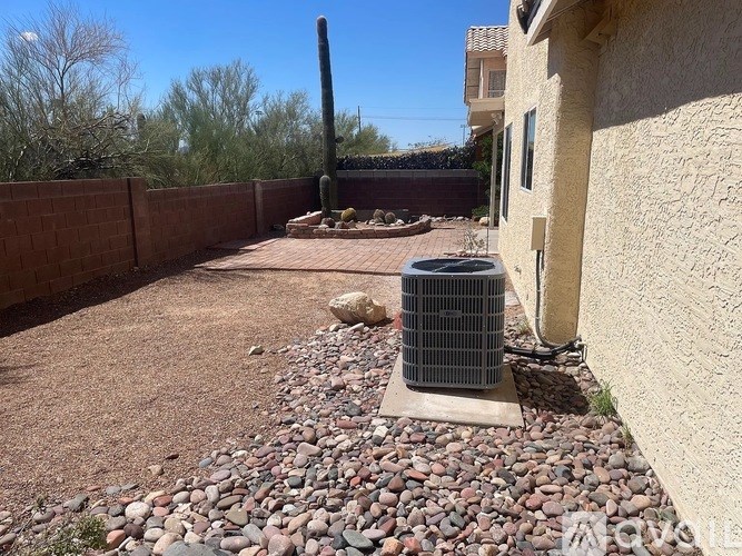 A patio with a rocky ground and a wall on one side.