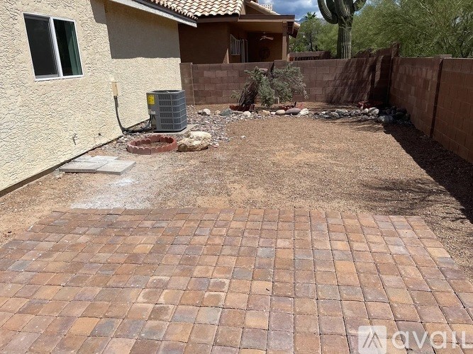 A backyard with a brick patio and a wall.