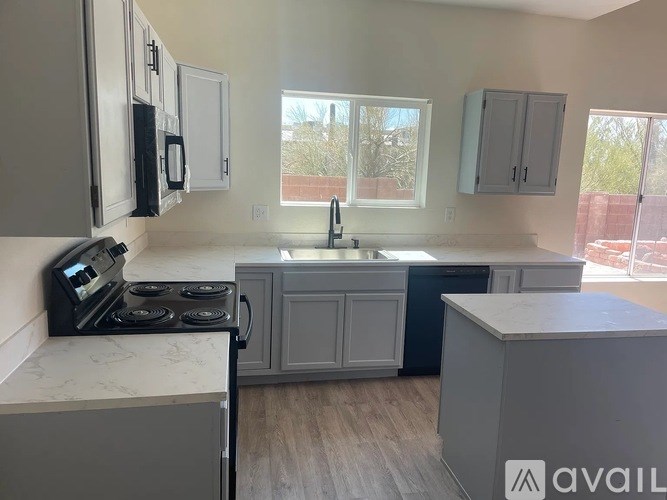 A kitchen with a stove, sink, and cabinets.