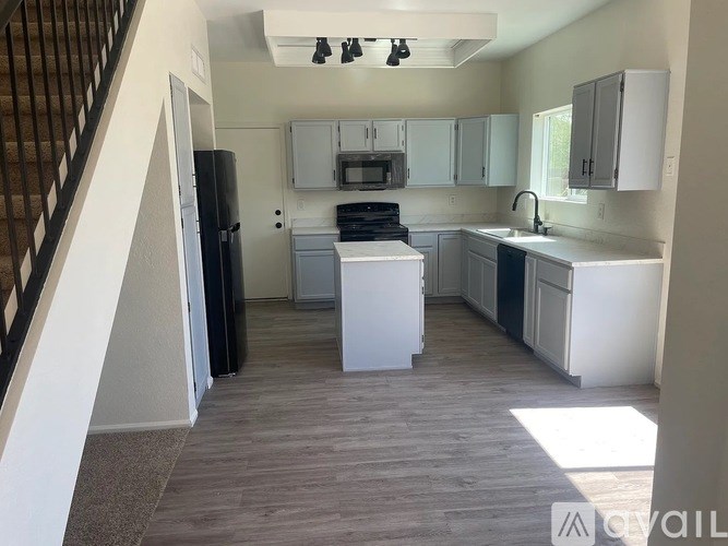 A kitchen with white appliances and a staircase on the left.