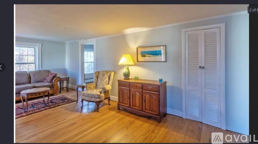A living room with a couch, chair, and wooden cabinet.