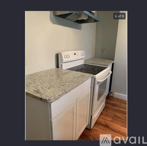 A kitchen with a white stove and a granite counter.