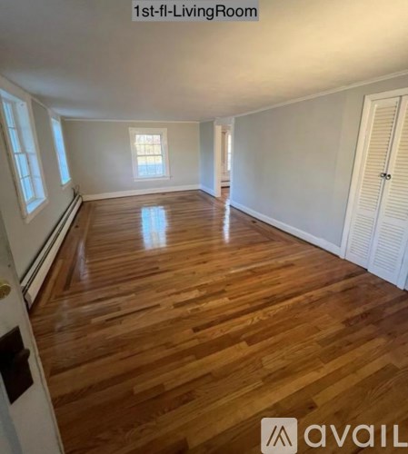 A living room with wooden flooring and white walls.