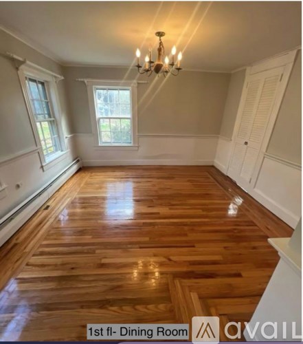 A dining room with wooden floors and a chandelier.