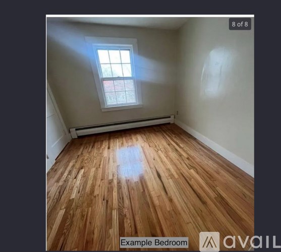 A bedroom with wooden flooring and a window.