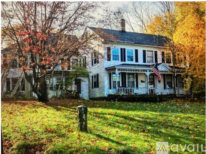 A white house with a porch and a flag on it.