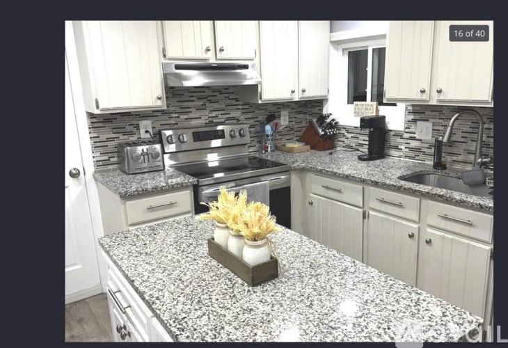 A kitchen with granite countertops and white cabinets.