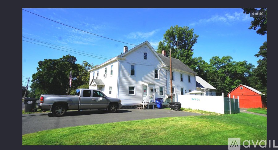 A white house with a red shed and a silver truck parked in front.