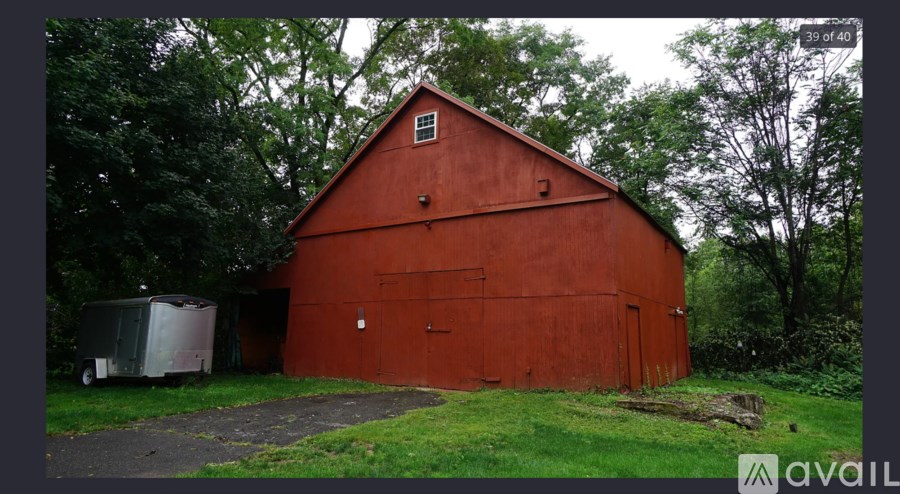 A red barn with a white door and a trailer in front of it.