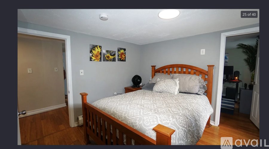 A bedroom with a bed, pillows, and a sunflower picture on the wall.