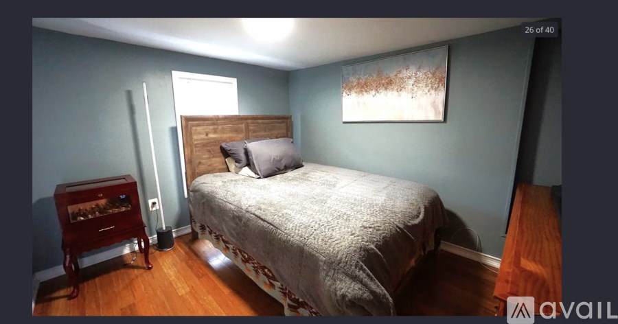 A bedroom with a bed, a nightstand, and a painting on the wall.
