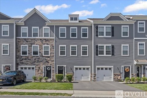 A modern two-story apartment building with a car parked in front.