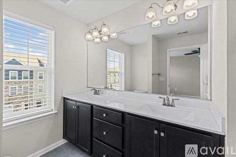 A bathroom with a large mirror, a sink, and a window.