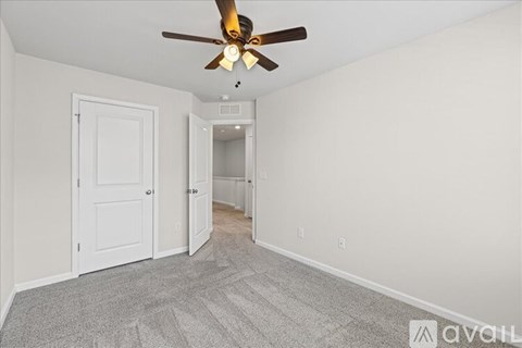 A room with a ceiling fan and carpeted floor.