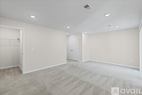 A spacious room with a carpeted floor and a door in the background.