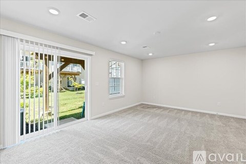 A spacious room with a carpeted floor and a sliding glass door leading to a backyard.