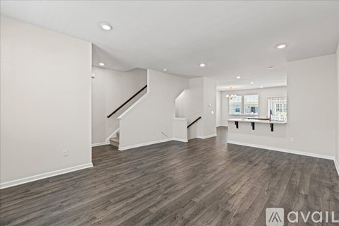A spacious room with wooden flooring and a staircase leading to another level.