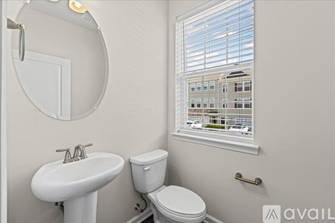A bathroom with a white sink, toilet and a window with blinds.