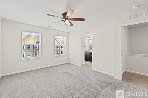 A spacious room with a ceiling fan and carpeted floor.