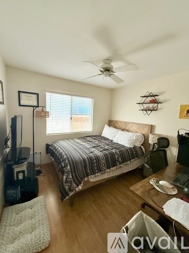 A bedroom with a bed, a television, and a ceiling fan.
