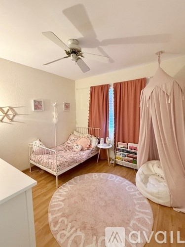 A baby's room with a white crib and a pink canopy.