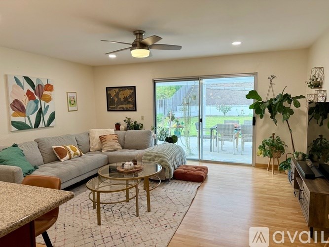 A living room with a grey couch, a coffee table, and a ceiling fan.