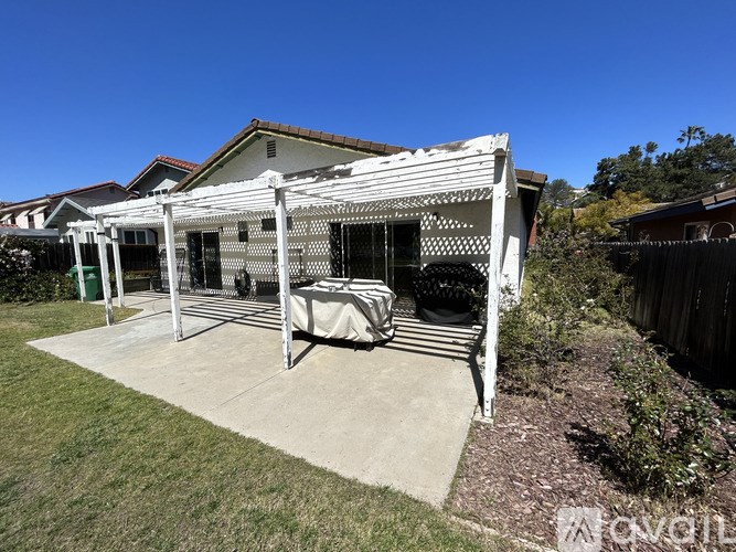 A white pergola is attached to a house.