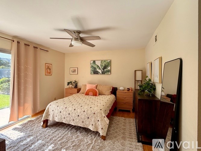 A bedroom with a bed, dresser, and window with curtains.