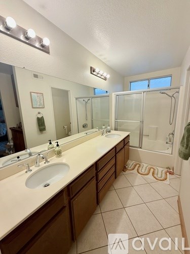 A bathroom with a large mirror, two sinks, and a shower.