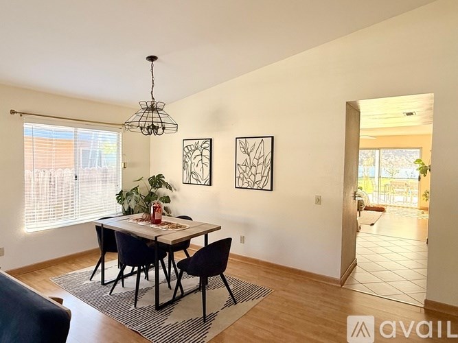 A dining room with a table set for two and a chandelier hanging from the ceiling.