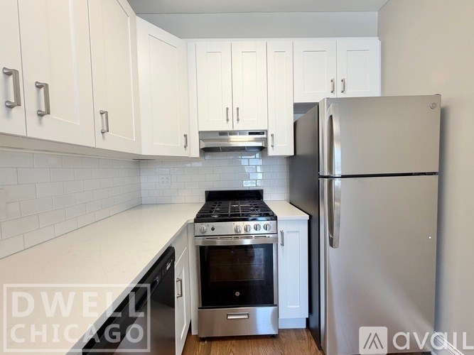 A kitchen with white cabinets and a stainless steel refrigerator.
