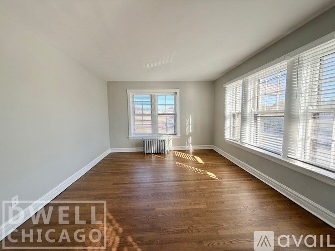 A room with wooden floors and a window with blinds.