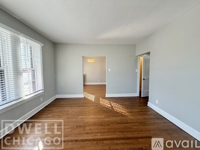 A room with wooden floors and white walls, with a door in the middle of the room.