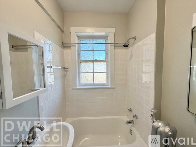 A white bathroom with a window and a bathtub.