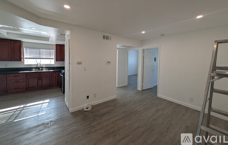A spacious room with wooden flooring and white walls, currently under renovation.
