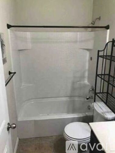 A bathroom with a toilet, tub, and towel rack.