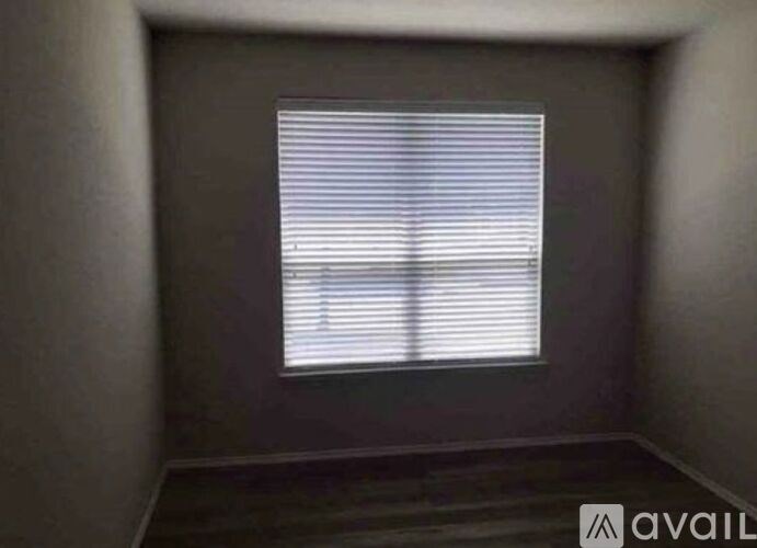 A room with a window covered by white blinds.