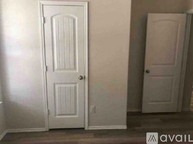 A white door with a panel design is in a room with a white wall.